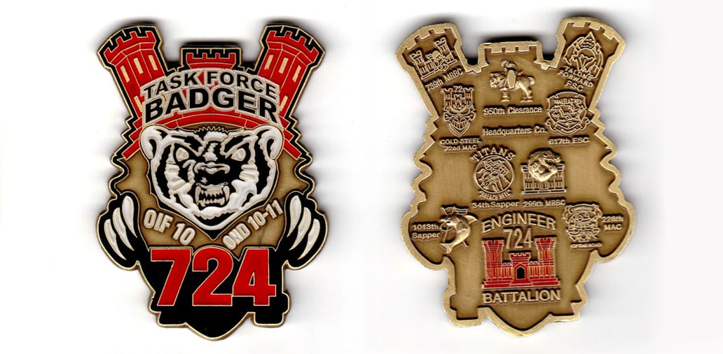 Shield shaped with castle turrets protuding above, Badger claws and the number 724 protruding on sides, brass colored co...