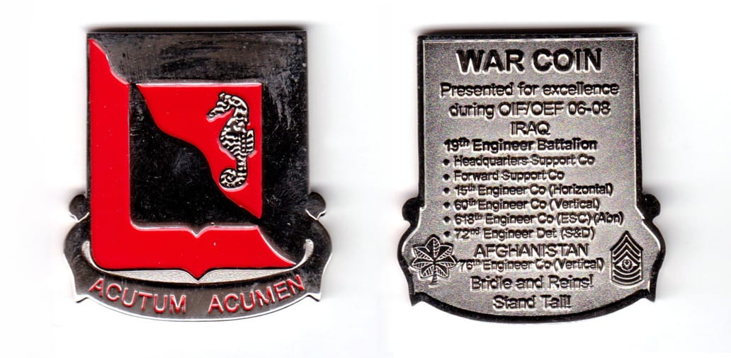 Shield shaped with banner mounted beneath, silver colored coin, 1-7/8 inches wide x 2 inches high.