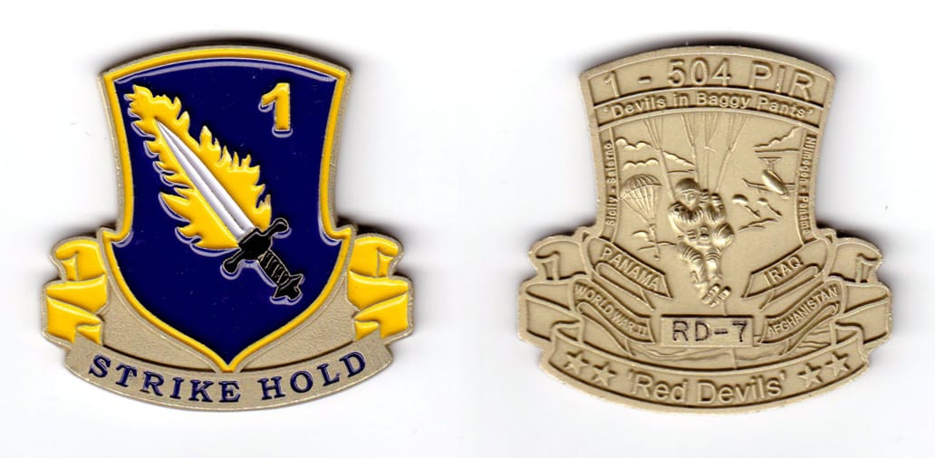 Shield shaped with banner mounted beneath, brass colored coin, 2 inches wide x 2 inches high.