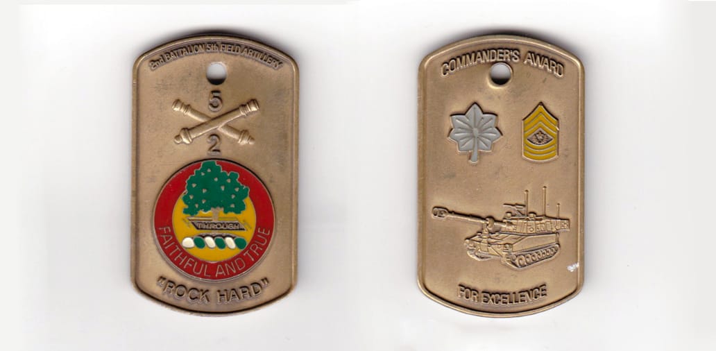 Dog tag shaped, brass colored coin, 1-1/4 inches wide x 2 inches high.