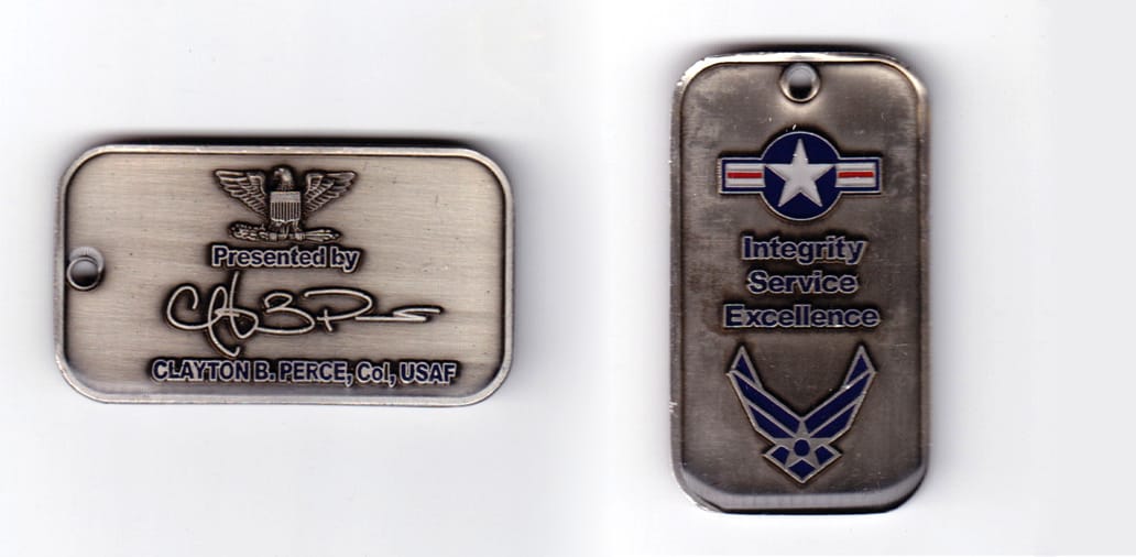 Dog tag shaped, pewter colored coin, 2-1/4 inches wide x  1-1/4 inches high.
