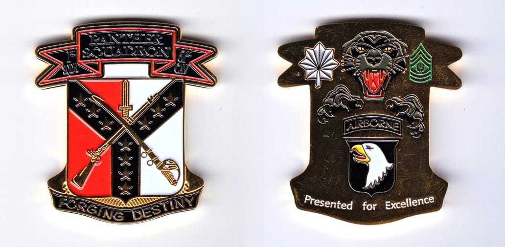 Shield shaped, gold colored coin, with banner mounted above and beneath, 1-7/8 inches wide x 2 inches high.