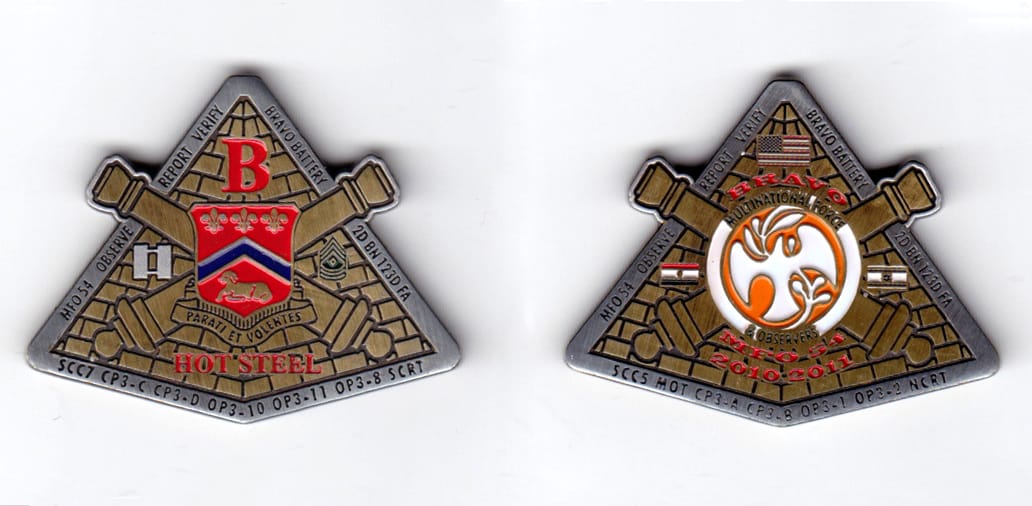 Triangualr shaped, with crossed cannons extending, pewter & brass colored coin, 2 inches wide x 1-9/16 inches high.