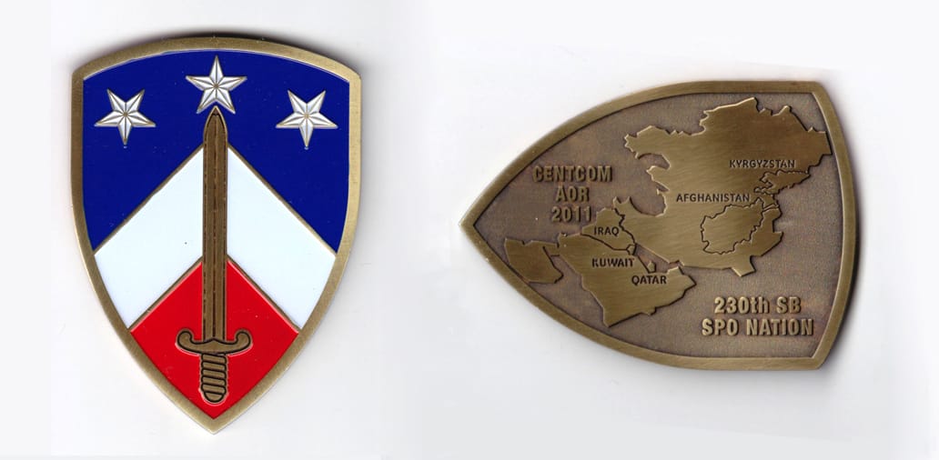 Shield shaped, brass colored coin, 2-1/8 inches wide x 3 inches high.