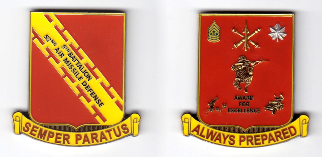 Shield shaped with banner mounted beneath, brass colored coin, 2-1/8 inches wide x 2-1/4 inches high.