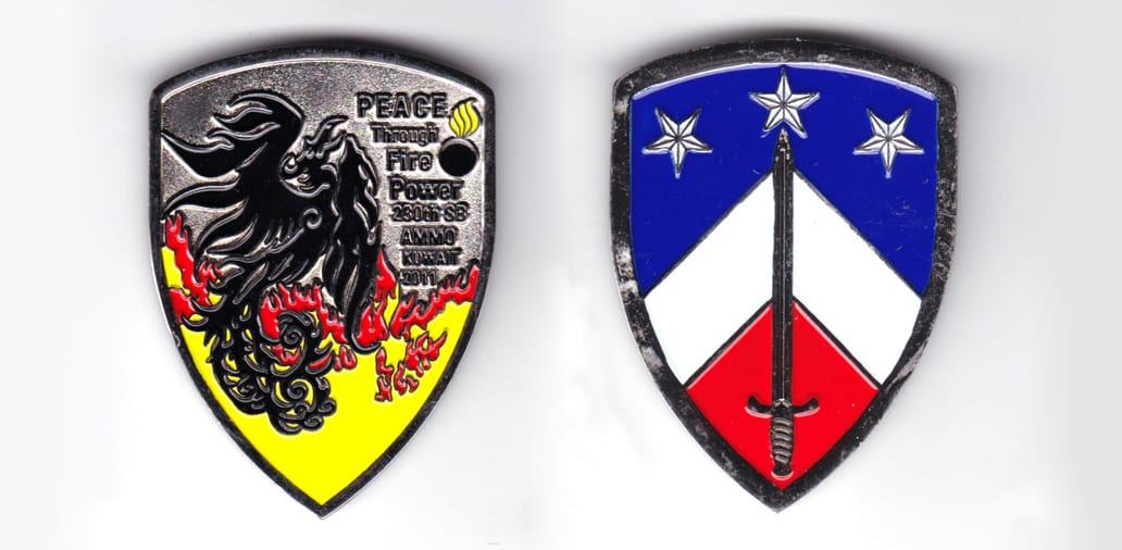 Shield shaped, silver colored coin, 1-1/4 inches wide x 2-1/4 inches high.