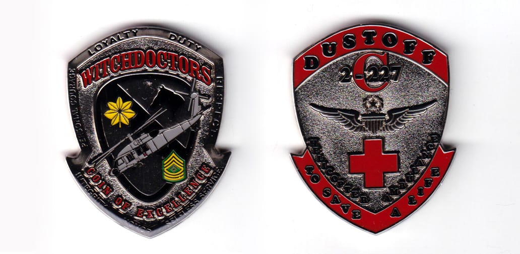 Shield shaped, silver colored coin, 2 inches high x 1-39/64  inches wide.