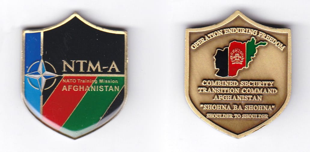 Shield shaped coin, antique brass in color, 1 1/2 inches high x 1 1/4 inches wide.