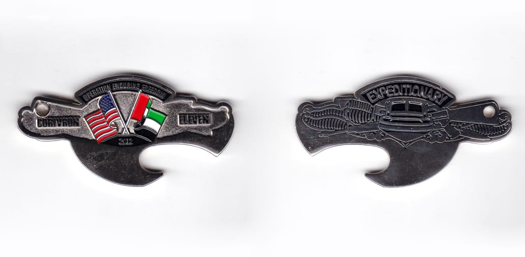 Bottle opener shaped coin, silver in color, 1 3/8 inches high x 2 3/4 inches wide.