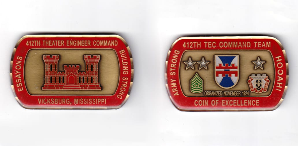 Dog tag shaped coin, antique brass in color, 1 43/64 inches high x    2 3/4 inches wide.