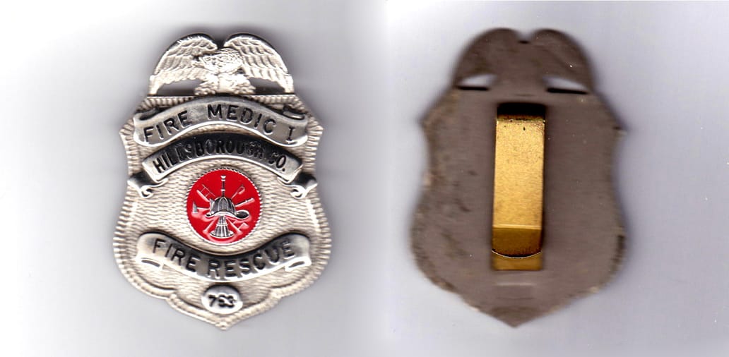 Standard badge shape, silver in color, 2 19/64 inches high x 1 43/64 inches wide.