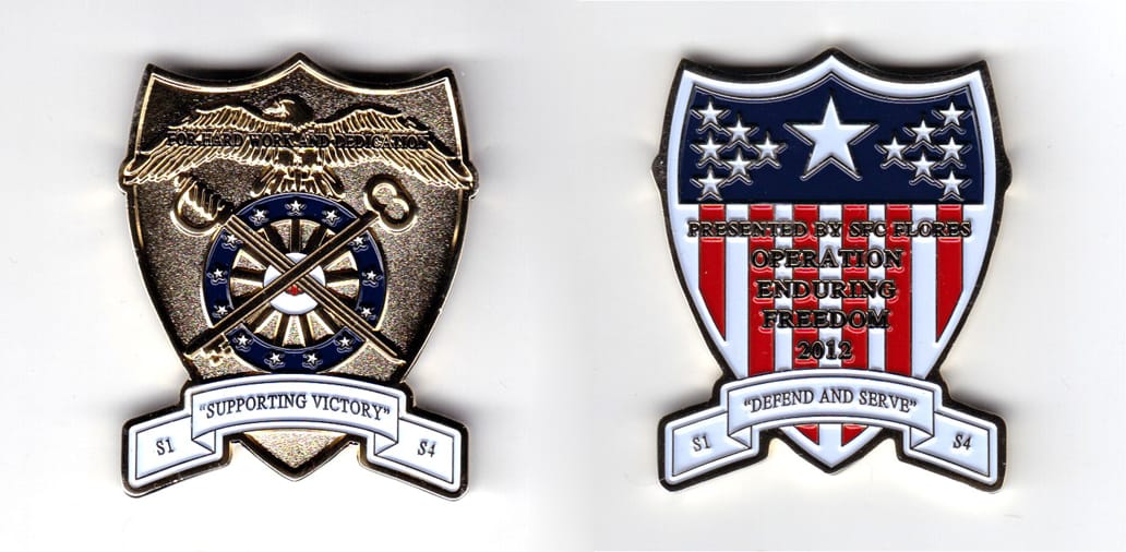 Shield shaped coin with banner across the bottom and extending to both sides, brass in color, 2 1/32 inches high x 1 5/8...