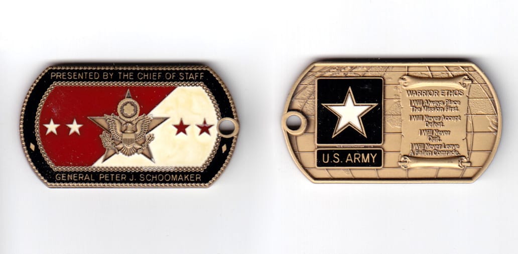 Dog tag shaped coin, antique brass in color, 1 11/64 inches high x      2 7/8 inches wide.