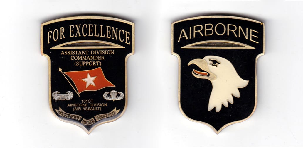 Shiel shaped coin with banner over, brass in color, 2 5/64 inches high x 1 21/32 inches wide.