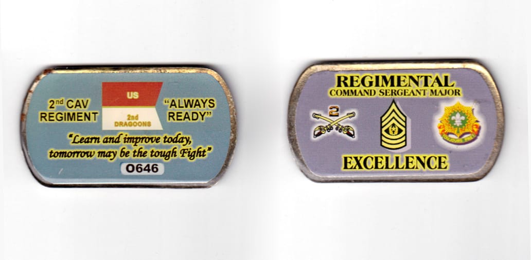 Dog tag shaped coin, pewter in color, 1 7/16 inches high x 2 37/64 inches wide.