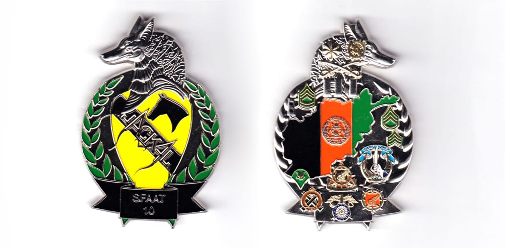 Round shaped coin with Jackal's head above and ribbon banner below, silver on color, 3 inches high x 2 inches wide.