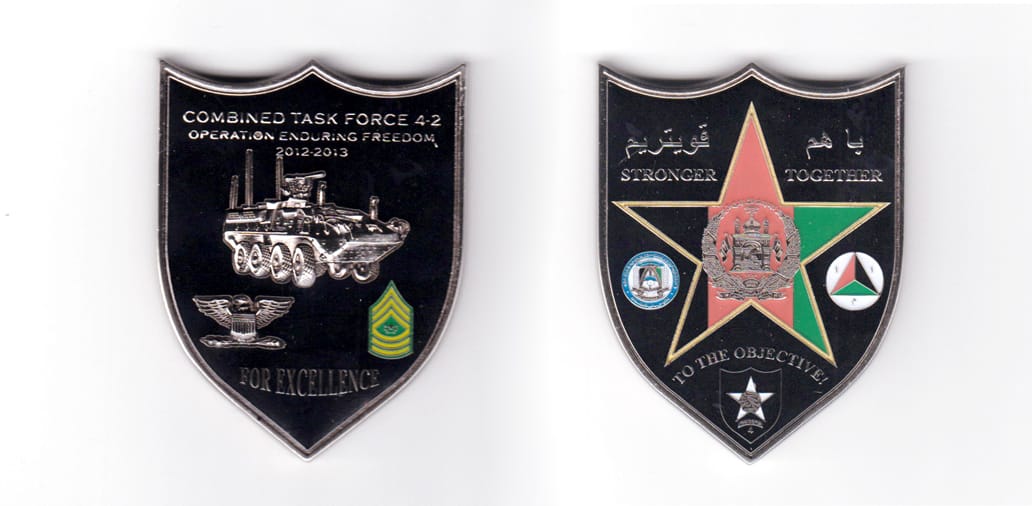 Shield shaped coin, pewter in color, 2 15/32 inches high x 1 29/32 inches wide.