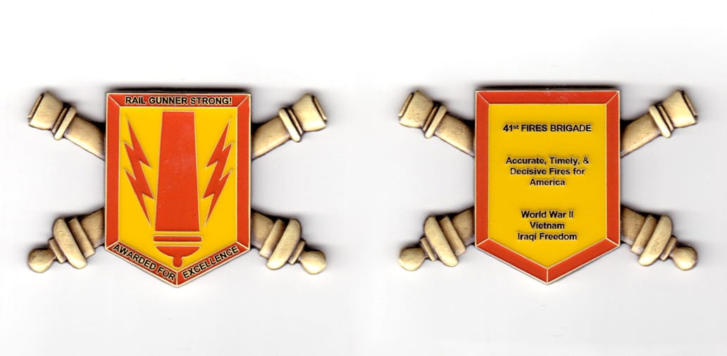 Shield shaped coin with crossed cannons behind and protruding from both sides, brass in color, 1 5/8 inches high x 2 3/6...