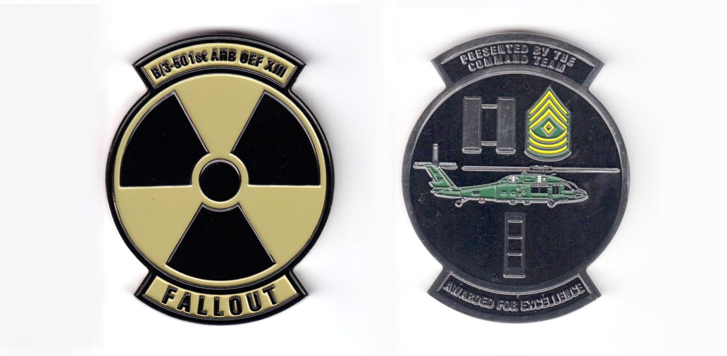 Round shaped coin with banner both above and below, silver in color, 3 inches high x 2 3/8 inches wide.