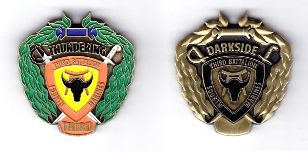 Shield shaped coin with crossed sabers ehind and with banners above & below and floral wreaths surrounding the rest, ant...