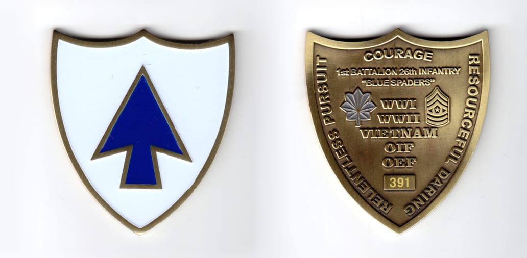 Shield shaped coin, brass in color, 2 1/2 inches high x 2 1/4 inches wide.