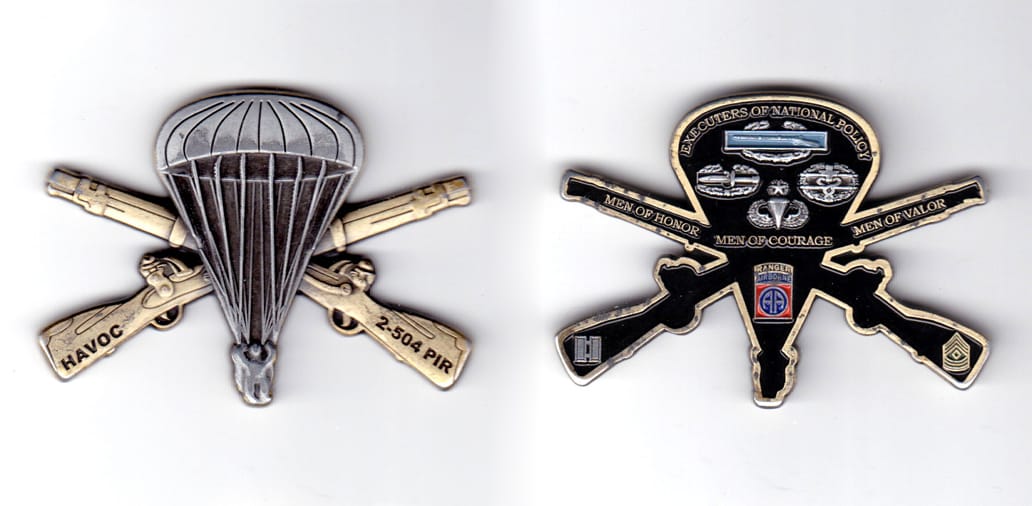 Parachute shaped coin with a pair of crossed rifles behind, antique brass in color, 1 3/4 inches high x 2 1/2 inches wid...