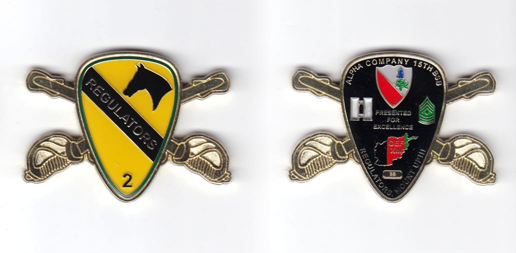 Shield shaped coin with crossed sabers behind, brass in color, 1 3/4 inches high x 2 1/2 inches wide.