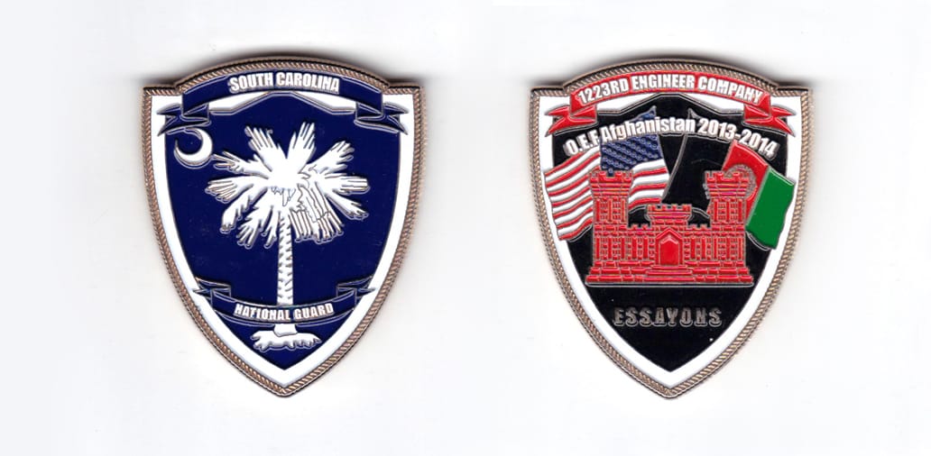 Shield shaped coin, gold in color, 2 inches high x 1 3/4 inches wide.