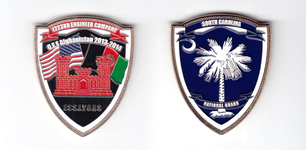 Shield shaped coin, brass in color, 2 inches high x 1 5/8 inches wide.