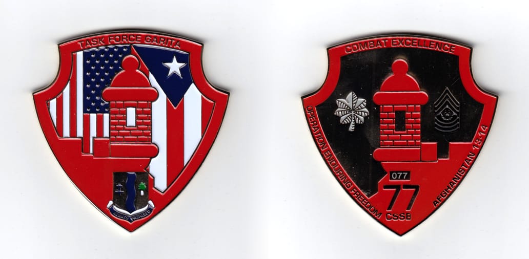 Shield shaped coin with circular indentations at the top left and right, brass in color, 3 inches high x 3 inches wide.