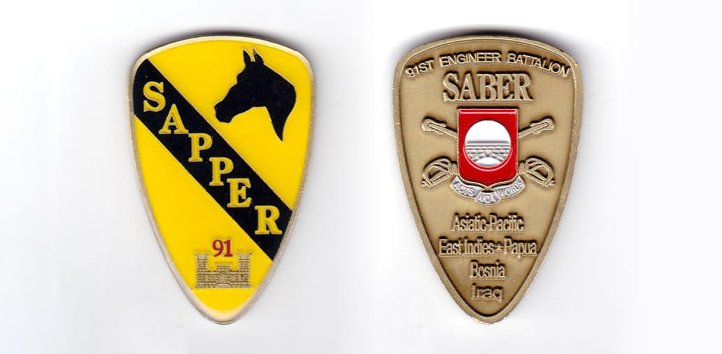 Shield shaped coin, antique brass in color, 2 inches high x 1 1/2 inches wide.