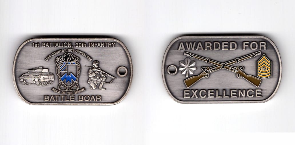 Dog tag shaped coin, pewter in color, 1 1/4 inches high x 2 1/4 inches wide.